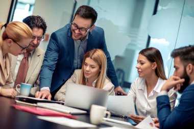 Tam konsantrasyon. Ofis masasında birlikte otururken çalışan ve iletişim kuran bir grup iş adamı..
