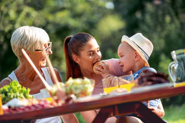 Happy family having lunch in their garden in summer.Leisure, food, family and holidays concept.