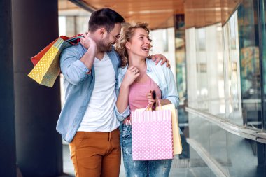 Satılık, tüketim ve insanlar kavramı-alışveriş torbaları vitrin City bakarak ile mutlu çift.