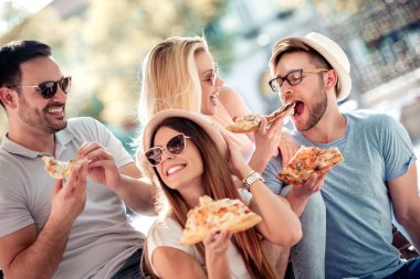 Bankta oturan ve pizza, yemek arkadaşlar açık havada eğleniyor. Tanışma, insanlar, yemek ve yaşam tarzı kavramı.