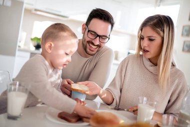 Üç kişilik aile kahvaltı yapıyor. Aile, aşk, mutluluk, yemek ve içki konsepti..