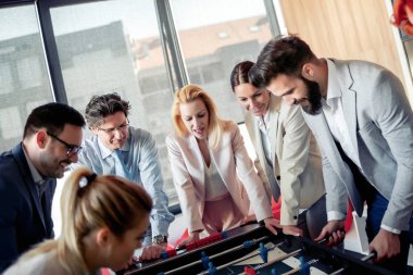 İş adamları birlikte harika vakit geçiriyorlar. Meslektaşlar modern ofiste masa futbolu oynuyorlar..