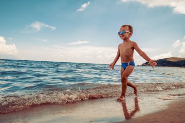 Tatile zevk kumsalda, eğleniyor şirin küçük çocuk.