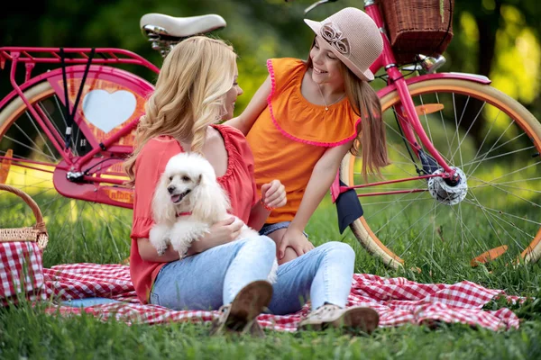 春の公園で彼女の娘と幸せな若い母親 彼らは犬と遊ぶ — ストック写真