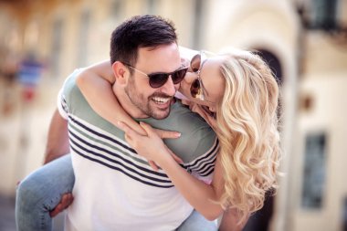 Dışarıda birbirine aşık gülümseyen bir çift. Sokakta sarılan mutlu genç bir çift..