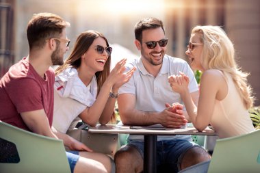 Grup arkadaşıyla kafede eğleniyor. İki kadın ve iki erkek konuşuyor, gülüyor ve birlikte zevk Café.