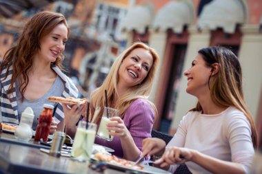 Neşeli arkadaşları pizza yemek, dışarıda eğleniyor. Dating, tüketim, gıda ve yaşam tarzı kavramı.