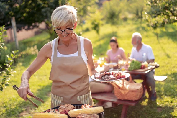 人和家庭概念 夏季花园聚会上烧烤烤架上的资深女性烤肉 — 图库照片