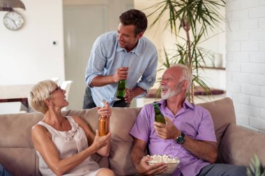 Üç içki bira, üst düzey aile yemek popcorns ve futbol oyunu evde izlerken. 