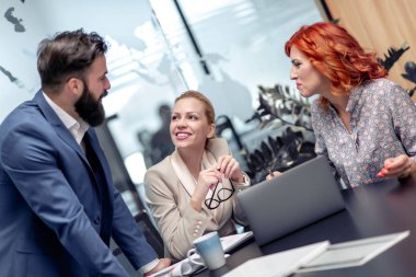 Bilgisayarları kullanan ve ofiste çalışırken gülümseyen iş adamları.