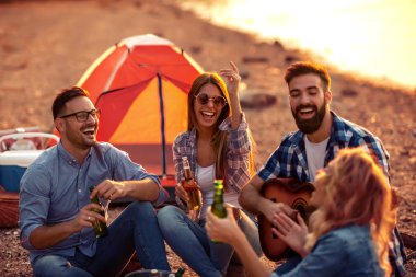 Mutlu arkadaş birlikte zevk, kamp üzerinde bira ve oyun gitar içme.