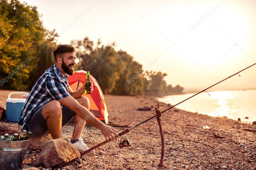 Young man fishing on a lake at sunset.