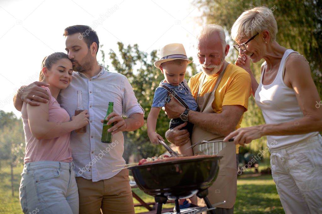 Happy big family gathered around the grill at picnic.Leisure,food,family and holidays concept.