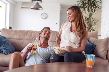 Evde zevk çift gülümseyen ve birlikte Tv izlerken.