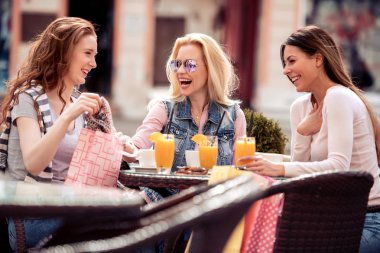 Yeni alımlarını birbirleriyle paylaşan üç genç kadın. Onlar kahve molası verdikten sonra alışveriş.