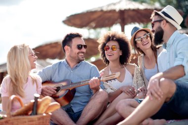 Mutlu arkadaş rahatlatıcı ve sahilde gitar çalmak. Beach partide eğleniyor.