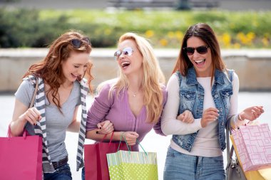 Satılık, kişi, turizm ve mutluluk kavramı. Şehrin alışveriş torbaları ile üç güzel kadın.