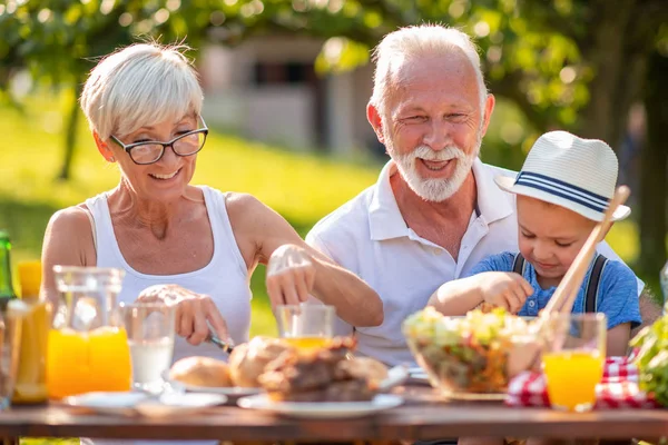 Happy family having lunch in summer garden.