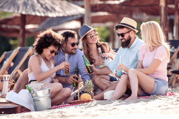 Friends enjoying in a good mood and picnic on the beach. Lifestyle, love, dating and vacation concept.
