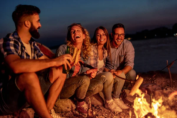 Friends having picnic around the fire.Group of young friends having picnic at night.