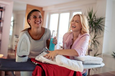 İki kadın elbise ütüyor ve evde elma şarabı içer. Birlikte eğlenin.