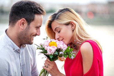Şehirde çiçekler ile genç romantik bir çift resmi.