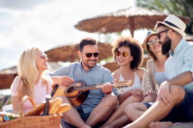 Mutlu arkadaş rahatlatıcı ve sahilde gitar çalmak. Beach partide eğleniyor.