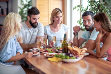 Genç arkadaşlar beyaz şarap ve yemek ile kutlamak, birlikte harika vakit geçiriyor.