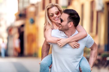 Dışarıda birbirine aşık gülümseyen bir çift. Sokakta sarılan mutlu genç bir çift..