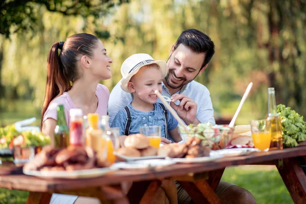 Family having a barbecue in the garden, eating and having fun together. Leisure, holidays, eating, people and food concept.