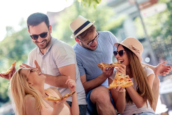 Close up of cheerful people eating pizza outdoors.Group of friends taking their slices of pizza.