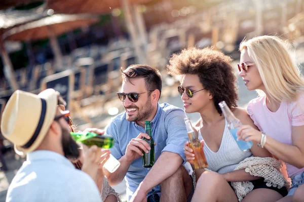 Geceleri plajda parti yapan arkadaşlar. Erkekler ve kadınlar bira içiyor.