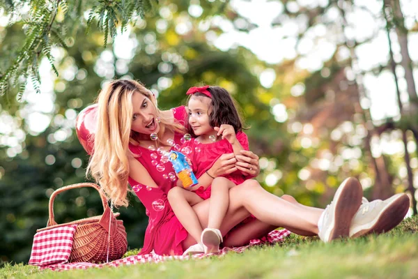 美しい母と娘が公園でシャボン玉を吹いている — ストック写真