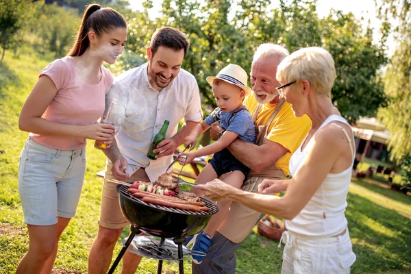 Happy big family gathered around the grill at picnic.Leisure,food,family and holidays concept.