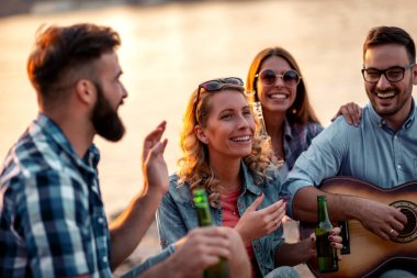 Arkadaşlar kamp yapıp gitar çalıyorlar. Birlikte harika vakit geçirmek.