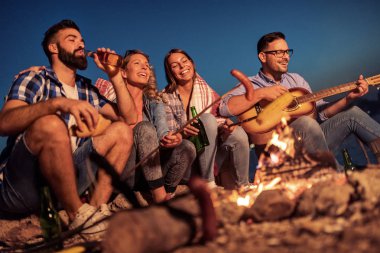 Geceleri ateşin yanında oturup, sosis ızgara ve büyük zaman sahilde olan arkadaş grubu.