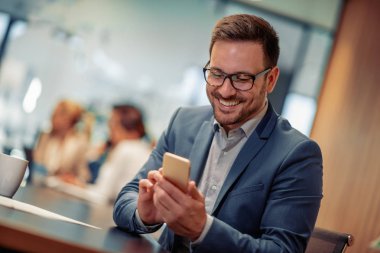 Ofiste cep telefonu kullanan gülümseyen işadamı fotoğrafı.