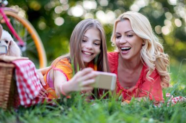 Anne ve çocuk eğleniyor, parkta selfie fotoğrafı çekiyor.