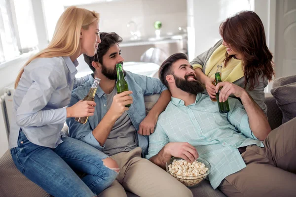 Group of friends sitting on the couch,eating popcorn and drinking beers. Friendship and party concept.