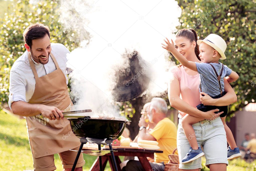 Family having a barbecue party in their garden in summer,enjoying together. 
