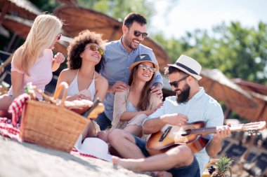 Mutlu arkadaş rahatlatıcı ve sahilde gitar çalmak. Beach partide eğleniyor.