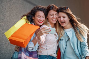Şehrin alışveriş torbaları ile üç güzel genç kadın. Satılık, moda, tüketim ve insanlar kavramı