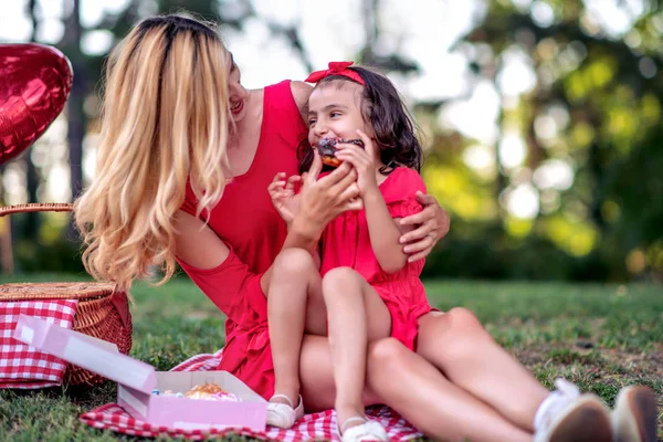 母と彼女の小さな娘は楽しんで 公園でドーナツを食べて — ストック写真