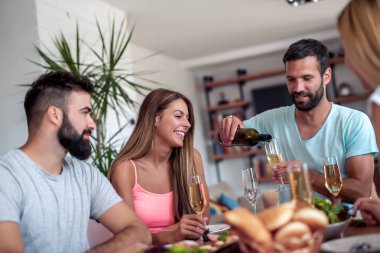 Evde birlikte yemeğe arkadaşları gülümseyerek. İnsanlar, yiyecek ve içecek, eğlence ve tatil kavramı.