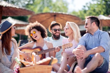 Mutlu arkadaş rahatlatıcı ve sahilde gitar çalmak. Beach partide eğleniyor.