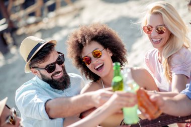 Sahilde birlikte eğlenen arkadaşlar, soğuk bira içen.