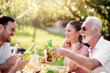 Mutlu aile yazın bahçelerinde öğle yemeği yiyor. Eğlence, yemek, aile ve tatil konsepti.