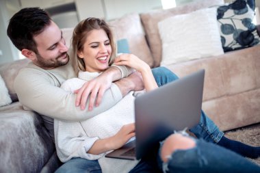 Mutlu genç çift katta oturan ve dizüstü bilgisayar kullanarak.