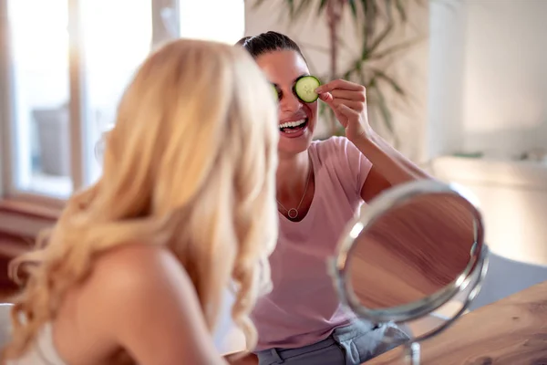 Duas Mulheres Alegres Segurando Pedaços Pepino Rosto — Fotografia de Stock