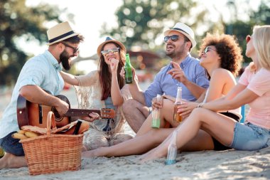 Sahilde gitar çalan genç adam. Grup arkadaş parti ve müzik dinleme.